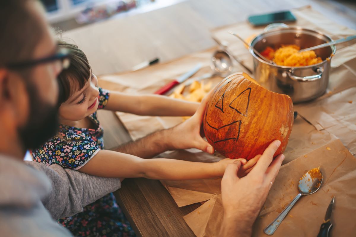 Father and daughter looking at their design before carving their pumpkin.