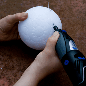 an image of an eyeball design being engraved into a round candle with a dremel tool 