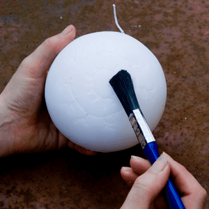 an image of a paint brush being used to brush away excess candle after the candle has been engraved 