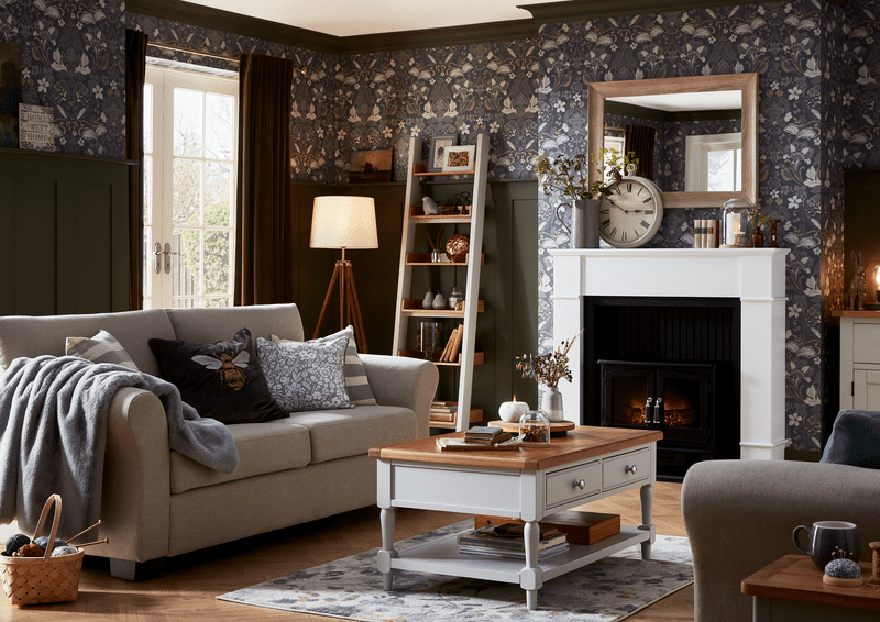 image of a lounge with dark patterned wallpaper a cream sofa with blue furnishings and a wooden coffee table