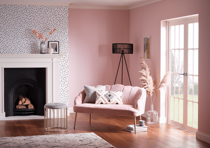 an image of a pink lounge with a pink sofa, pampas grass and a black and white spotty wallpapered feature wall
