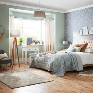 an image of a blue and green bedroom with a lamp a chair a dressing table and bed and rug