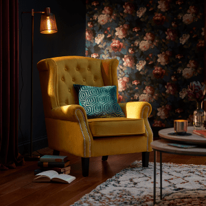 an image of a dark wallpapered room with a mustard yellow occasion chair with a blue patterned cushion