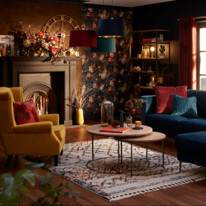 an image of a dark and cosy living room with mismatched furniture, a rug, cushions, sofa and occasion chair