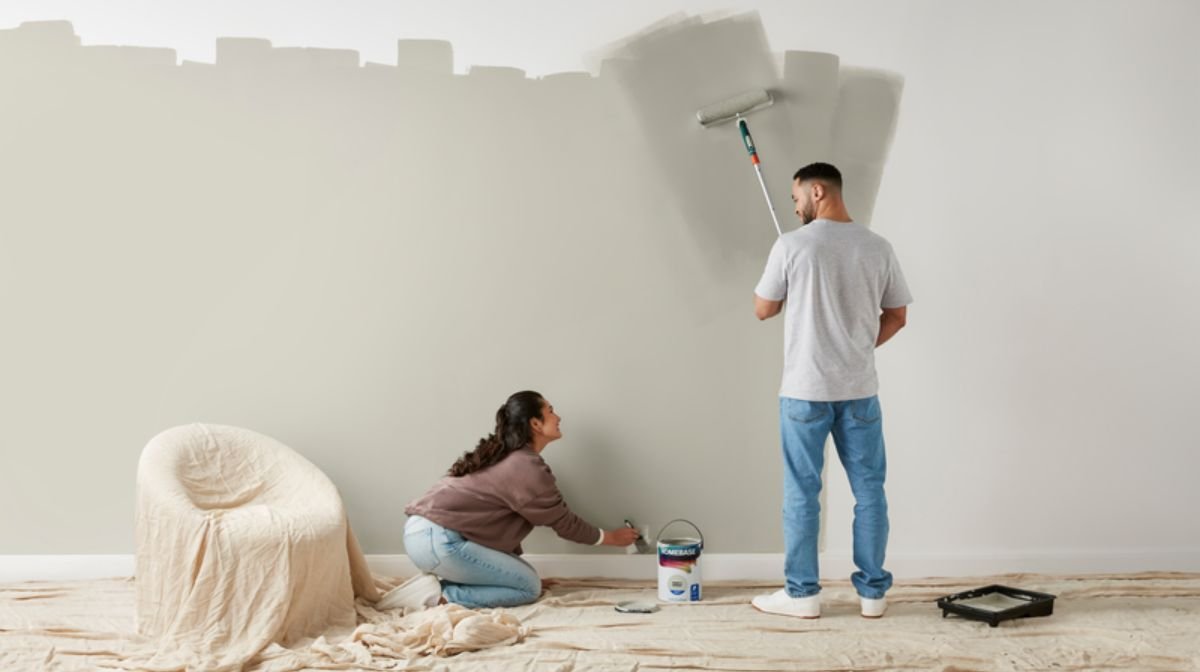 Couple painting a wall pale green