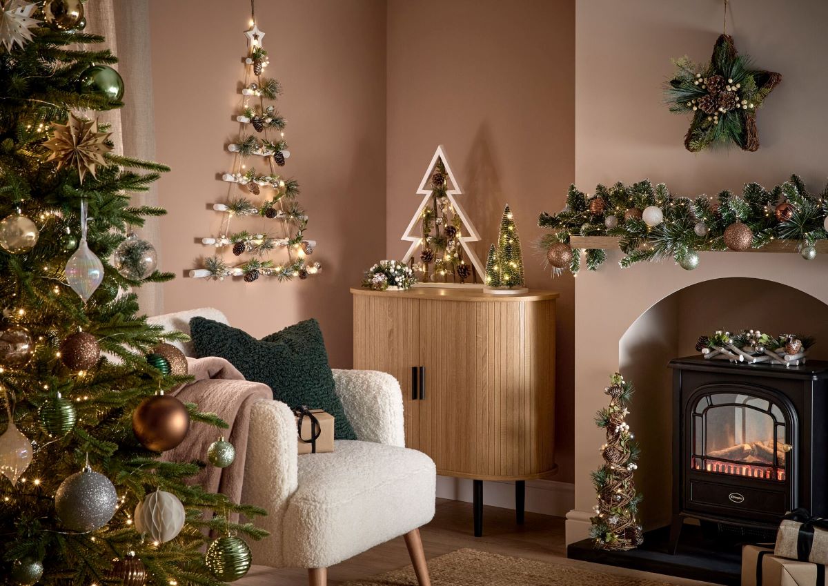 A beige living room decorated with a Christmas tree, lights, a garland and green, cream and bronze-toned baubles