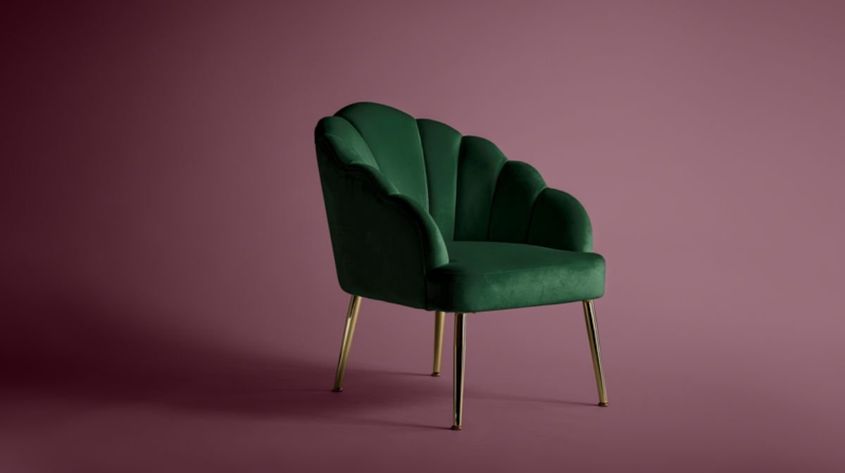 Green velvet accent chair against plum-coloured backdrop