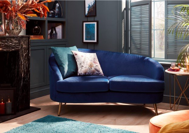 Image of a royal blue modern chaise longue decorated with two accent cushions in a modern blue living room furnished with copper decorations and a teal rug.