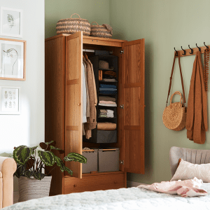 Small bedroom with open wardrobe decorated with a gallery wall and a row of coat hooks