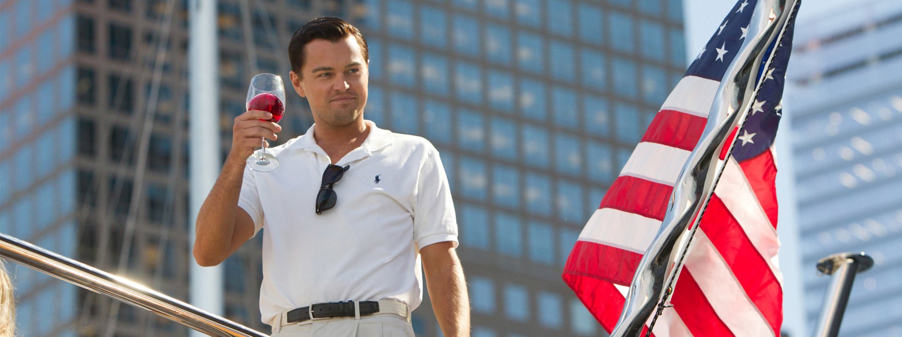Jordan Belfort (Leonardo DiCaprio) stands beside the American flag raising a glass of wine in The Wolf of Wall Street (2013)