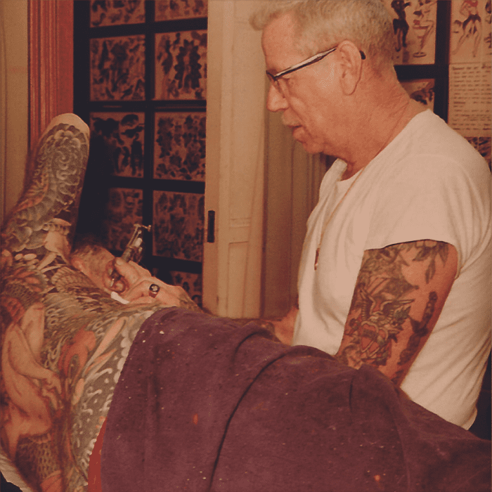Sailor Jerry tattooing his traditional art style on a patron