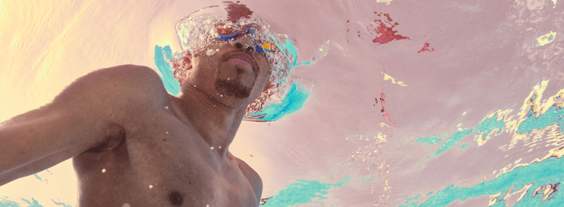 A man swimming and wearing Speedo goggles