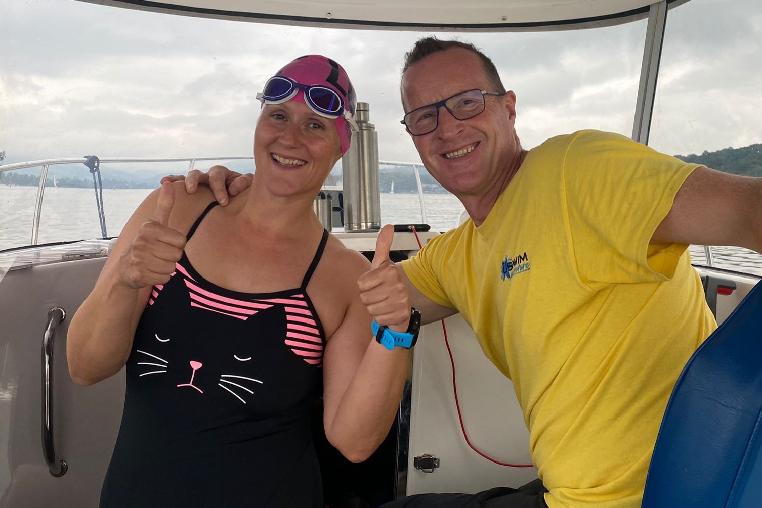 Two swimmers smile on boat