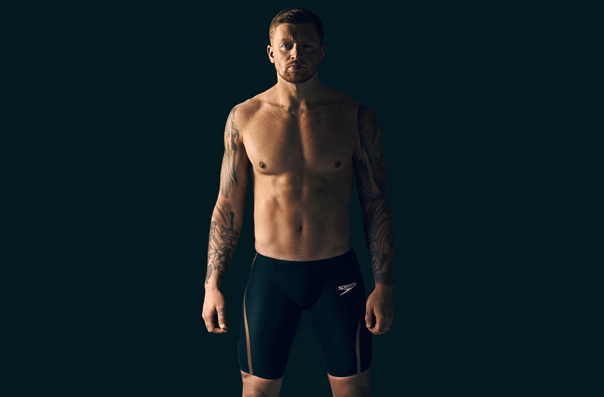 Adam Peaty stands proudly infront of black background
