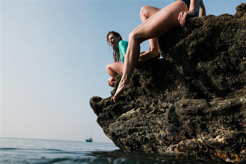 Group sits on rocks in Speedo swimwear