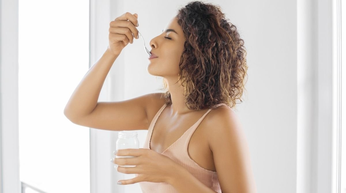 Una giovane donna che mangia uno yogurt pieno di batteri buoni, benefici per la salute intestinale