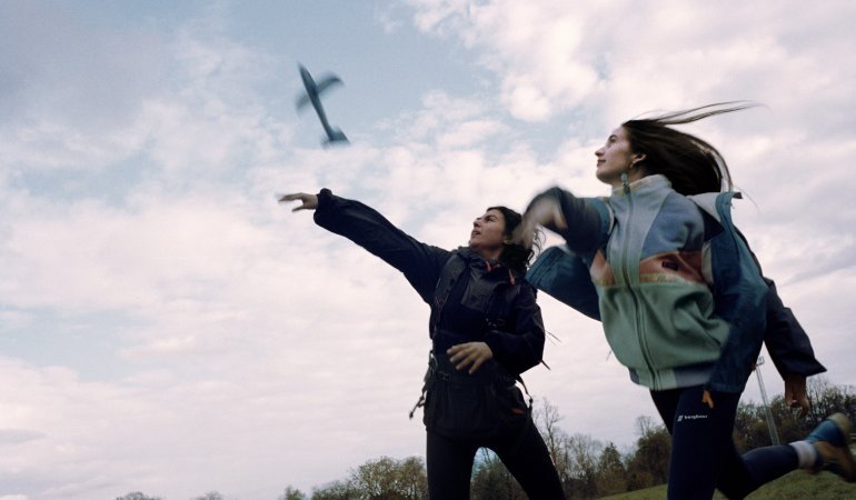 Teenagers throw a paper airplane into the sky