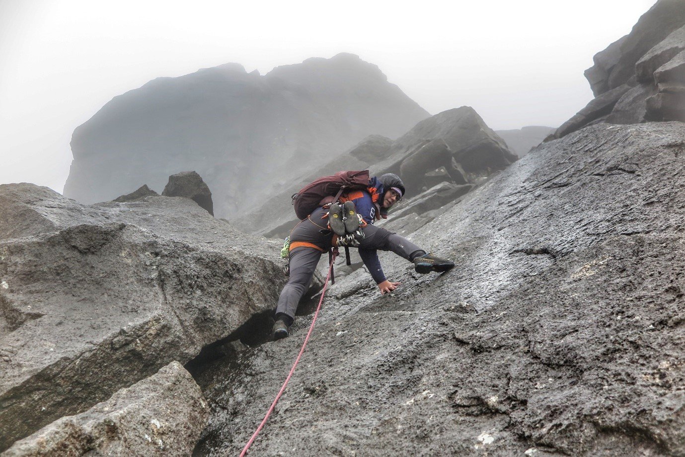 Anna climbing steep rock in Berghaus waterproof clothing