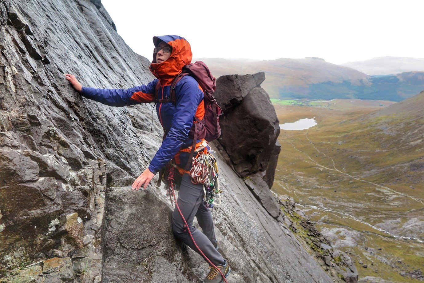 Anna stands on cliff in orange and purple Berghaus waterproofs