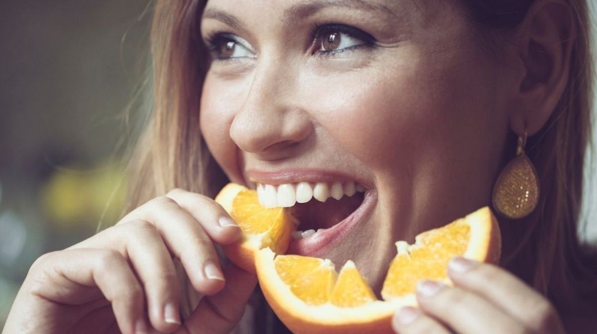한 여성이 비타민 C가 풍부한 오렌지를 먹고있다.