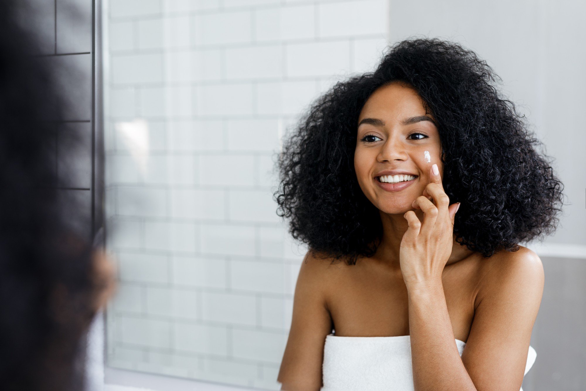 woman applies moisturizer in the mirror 