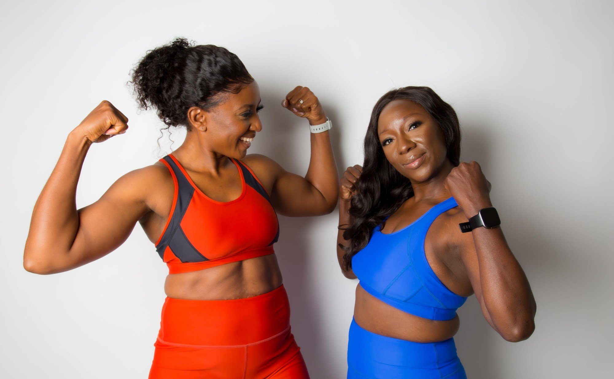 Two women happily flexing their muscles after a workout