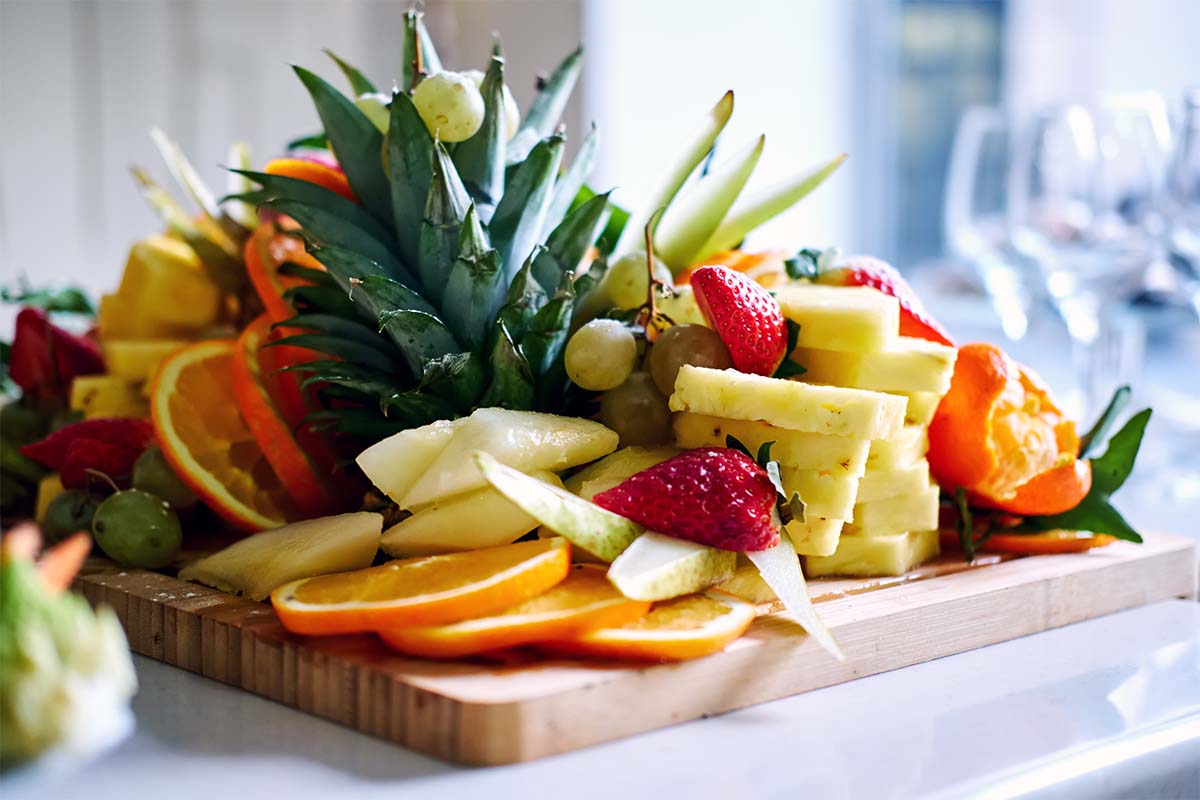 Pineapple, orange and berries on chopping board 