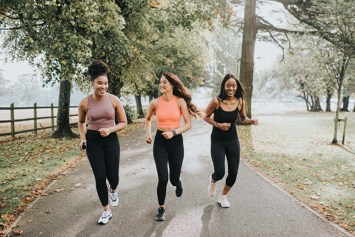 three women running together through a park