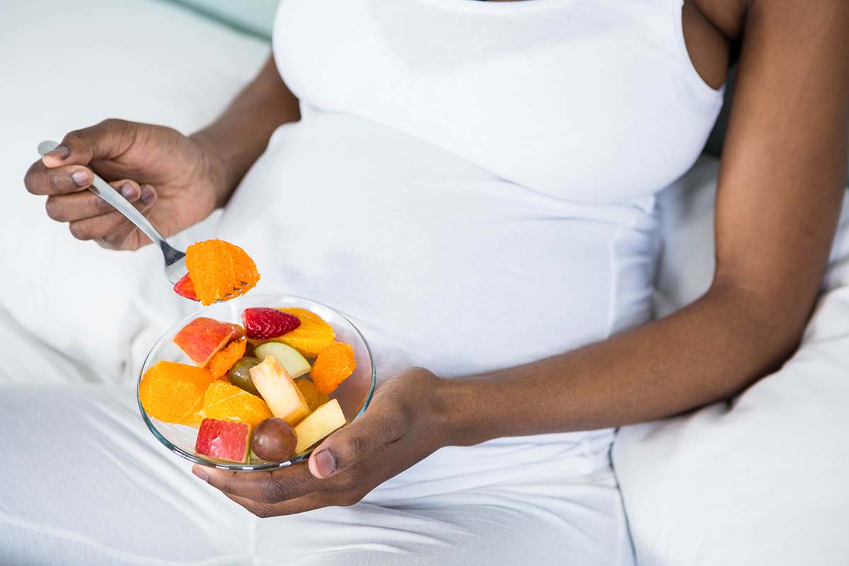pregnant person eating fruit salad