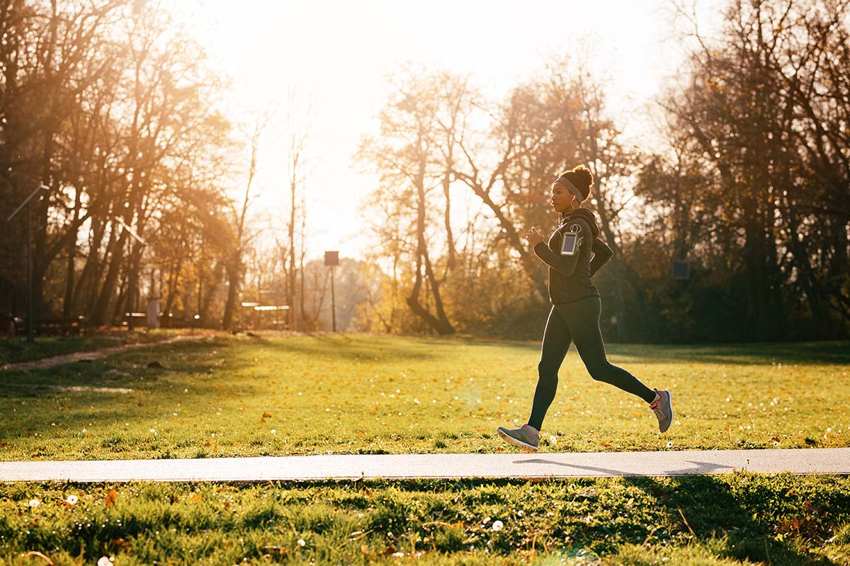 woman running through park on sunny day