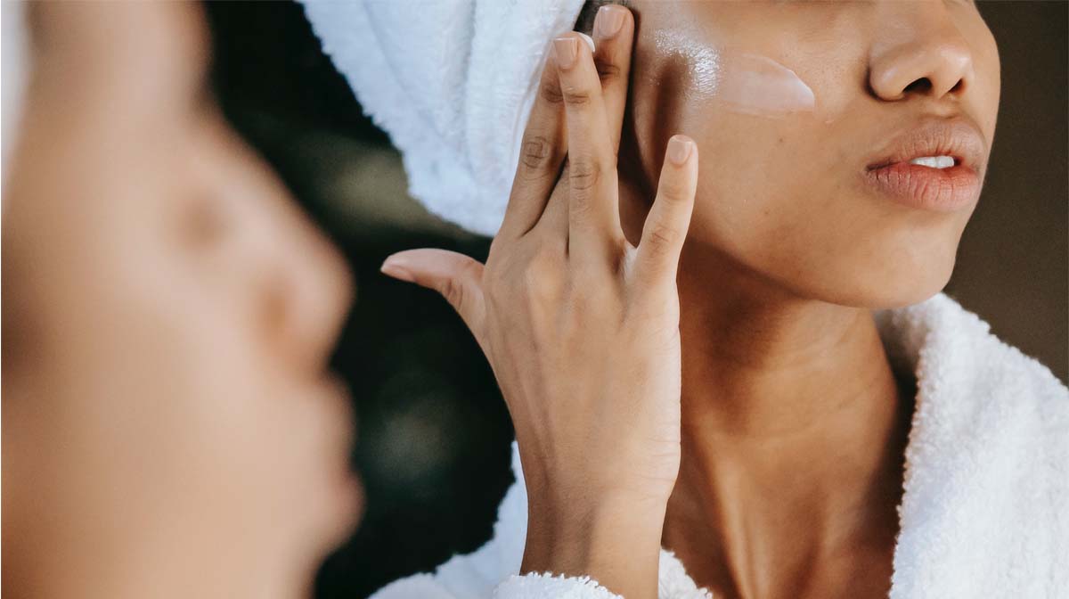 women applying face cream in the mirror