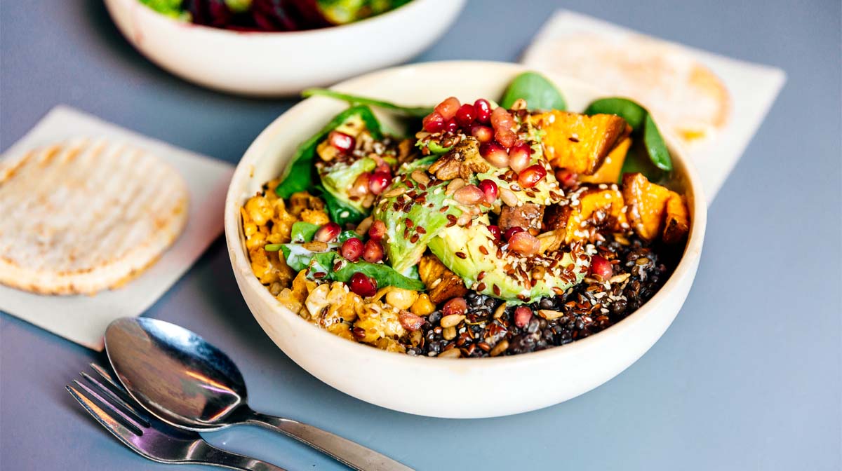Nourish bowl topped with mixed seeds and pomegranate