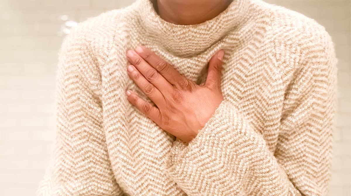 Woman with hand on chest in warm jumper