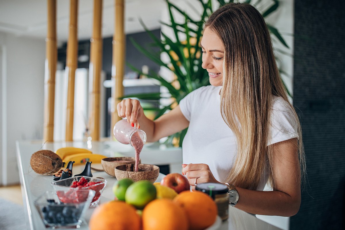 woman pours fruit smoothie into bowl