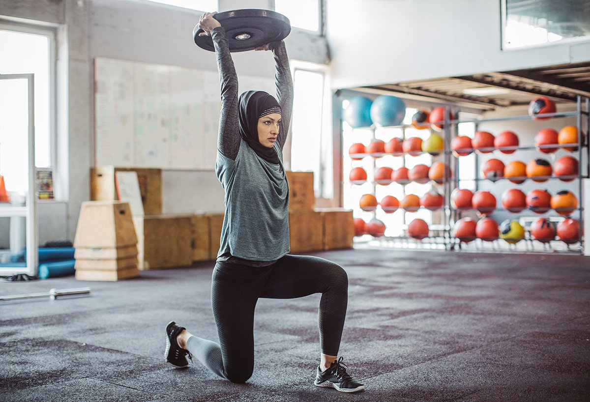 Woman lunging with weight plate 