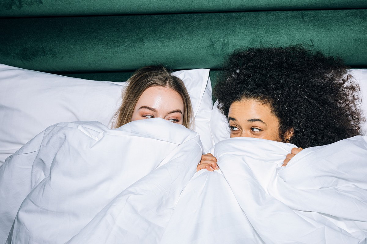 Two women in bed looking at each other