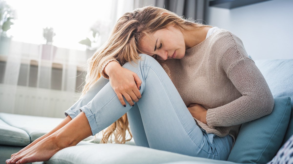 woman with stomach cramps curled up on sofa