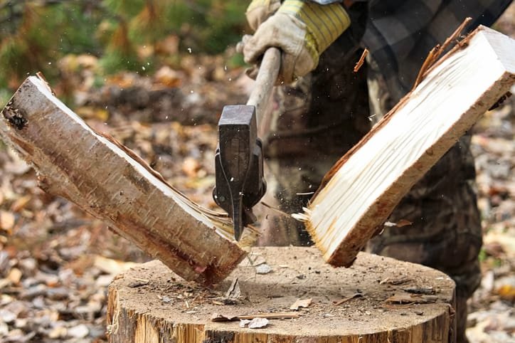 Person chops wood on log