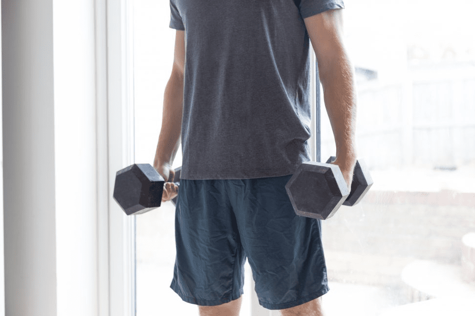 man stands with a dumbbell in each hand