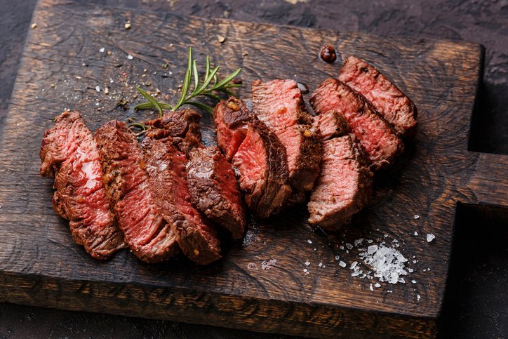 Steak cut into slices on a wooden chopping board