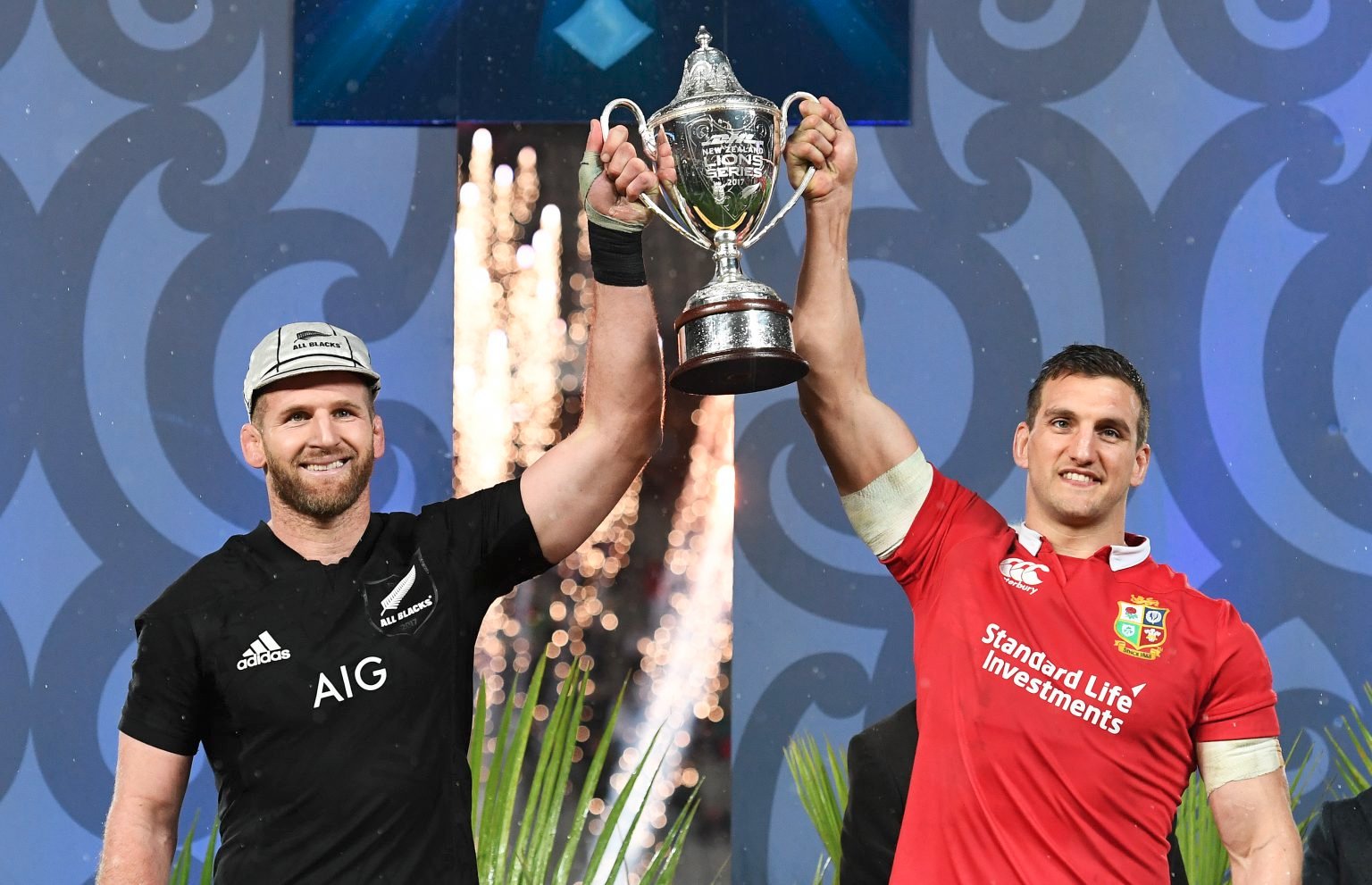 Lions and All Black players lift trophy together