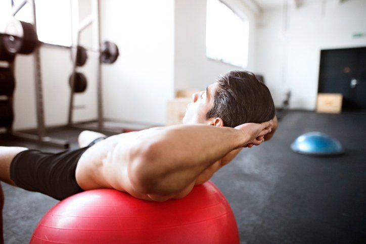 Man performs sit ups on exercise ball