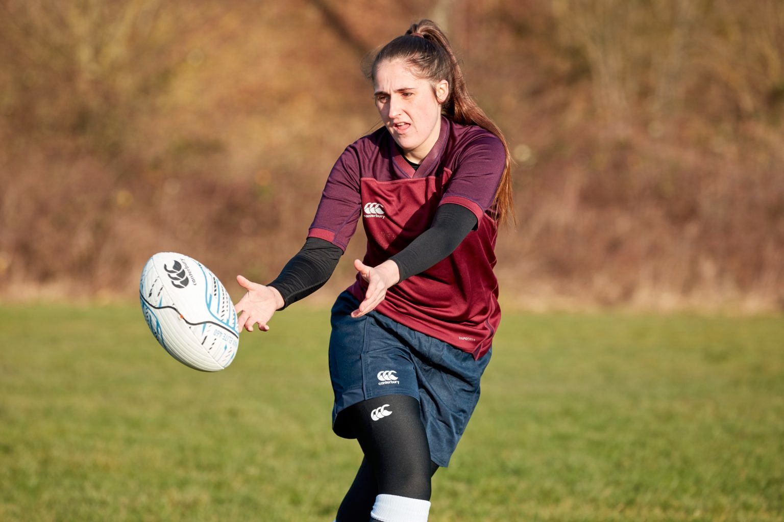 Person passes rugby ball to their right