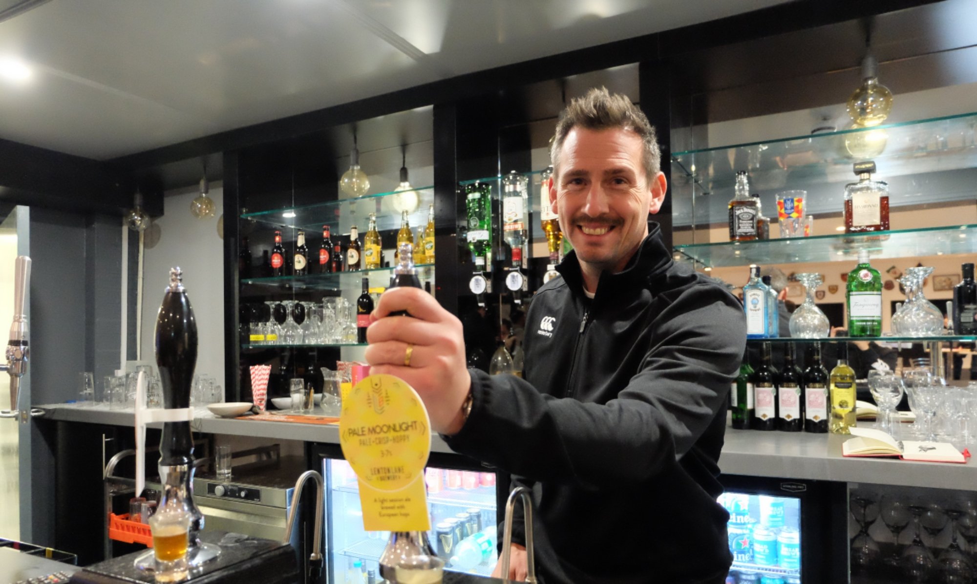 Man in Canterbury gear pulls pint behind clubhouse bar