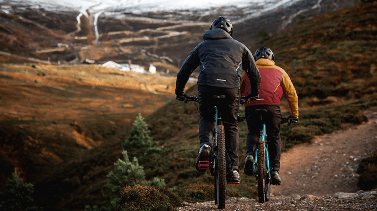 Two cyclists head down into a valley