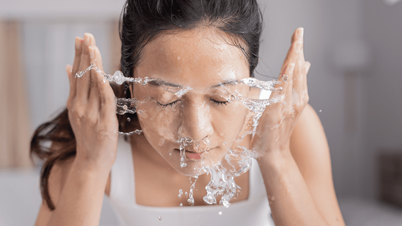 woman splashing and cleansing face 