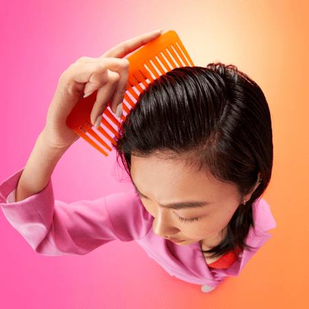 brown haired woman using an orange comb