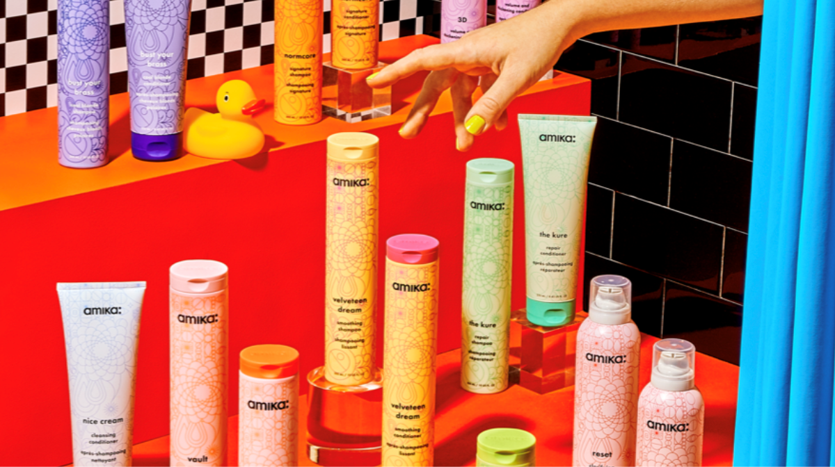 the full of amika shampoo and conditioners displayed with a hand hovering to pick up one of the products