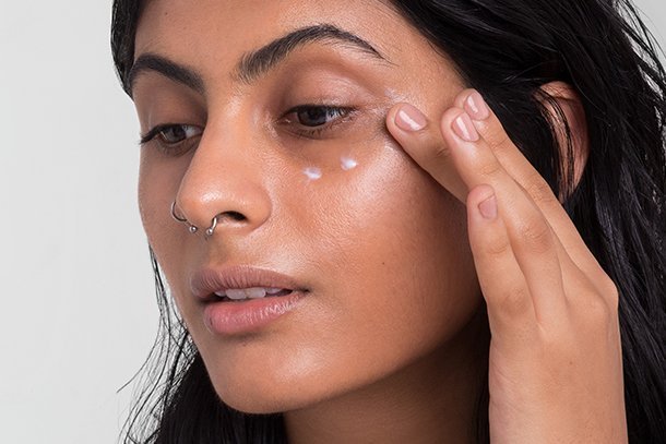 model applying eye cream onto her face