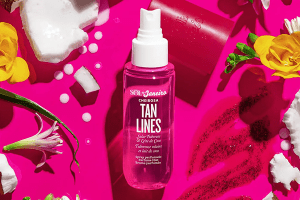 sol de janeiro tan lines perfume mist in a magenta backgroun surrounded by flowers, coconuts 